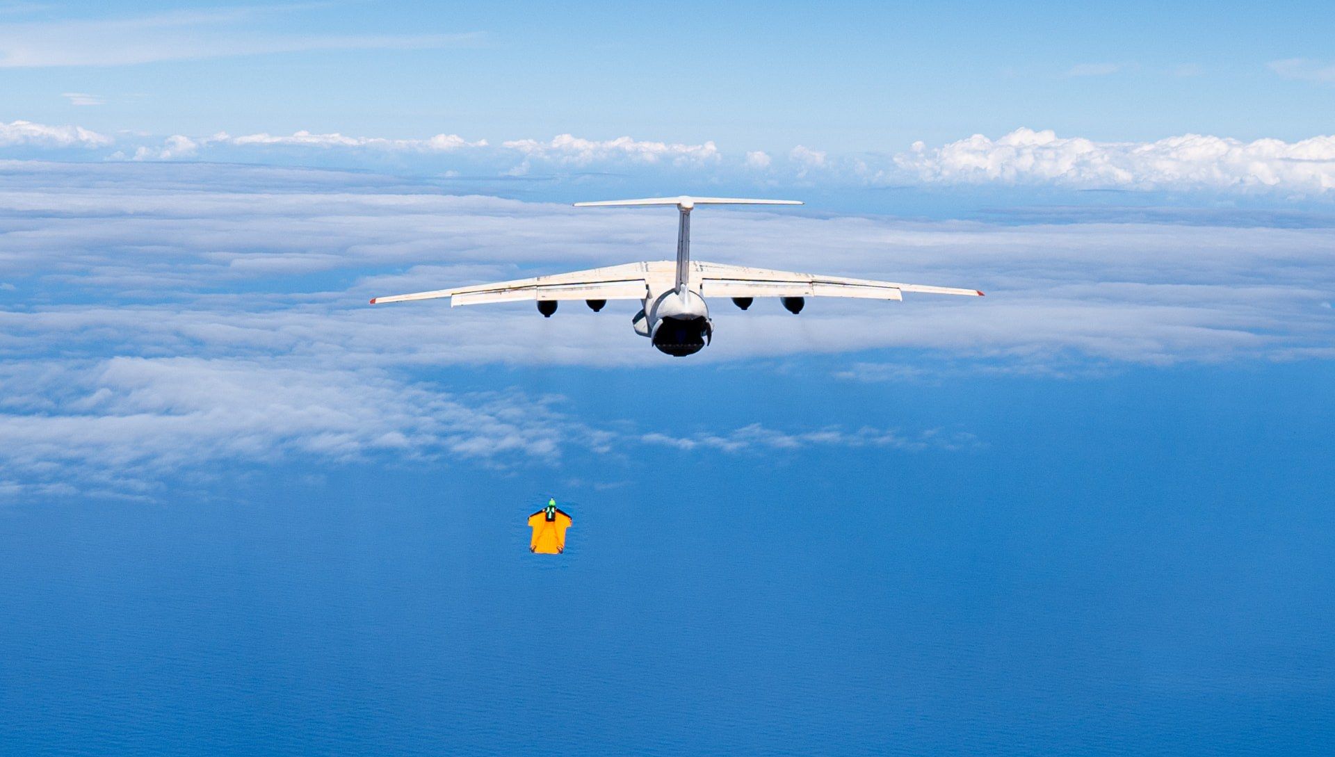 Cargo aircraft in flight with a wingsuit pilot below